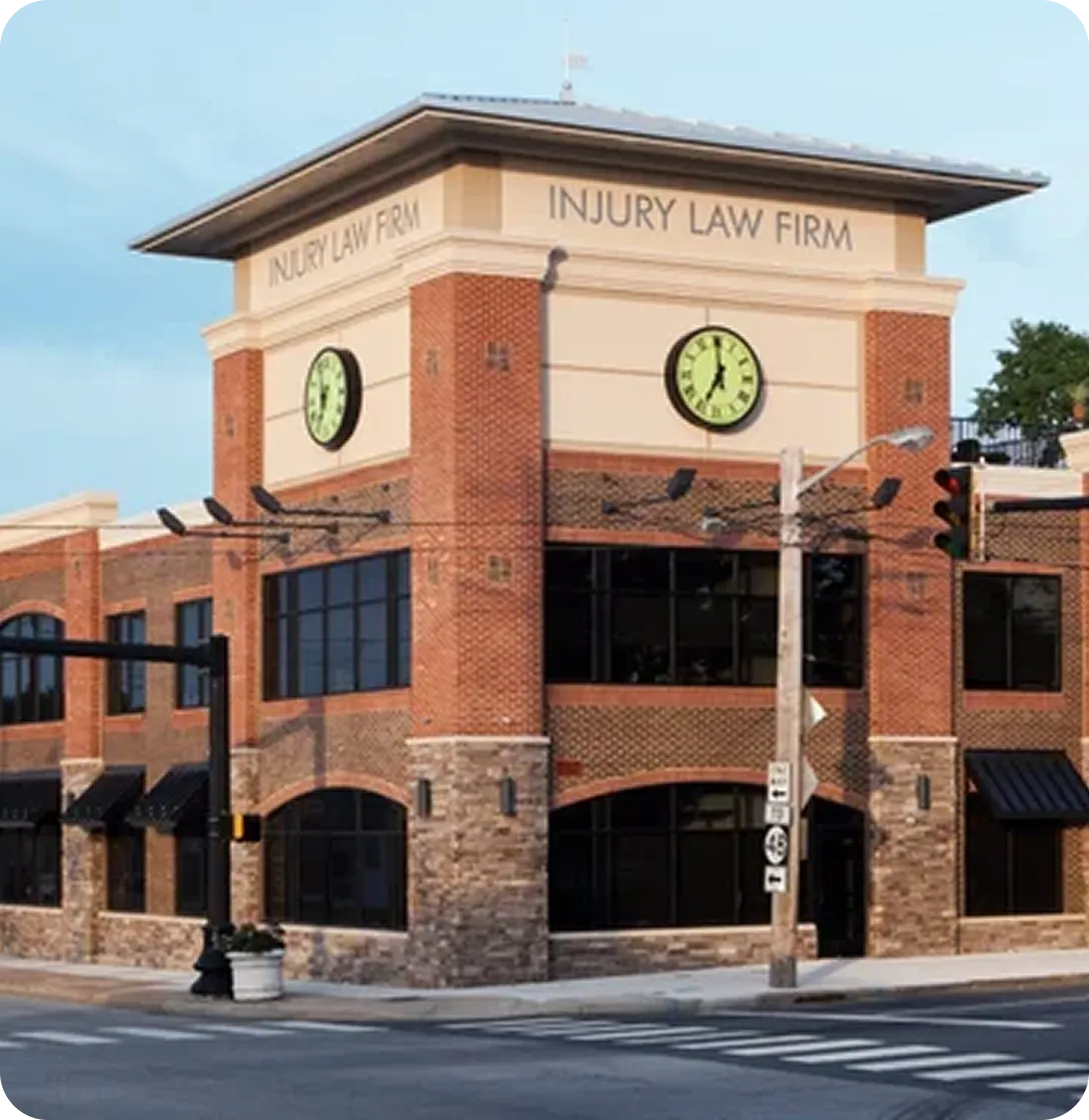 Two-story brick and stone building with clocks and "Injury Law Firm" signage at street corner.