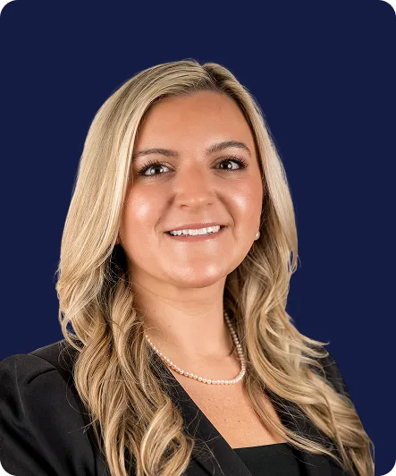 Professional headshot of a smiling woman with long blonde hair, pearl necklace, and black blazer.